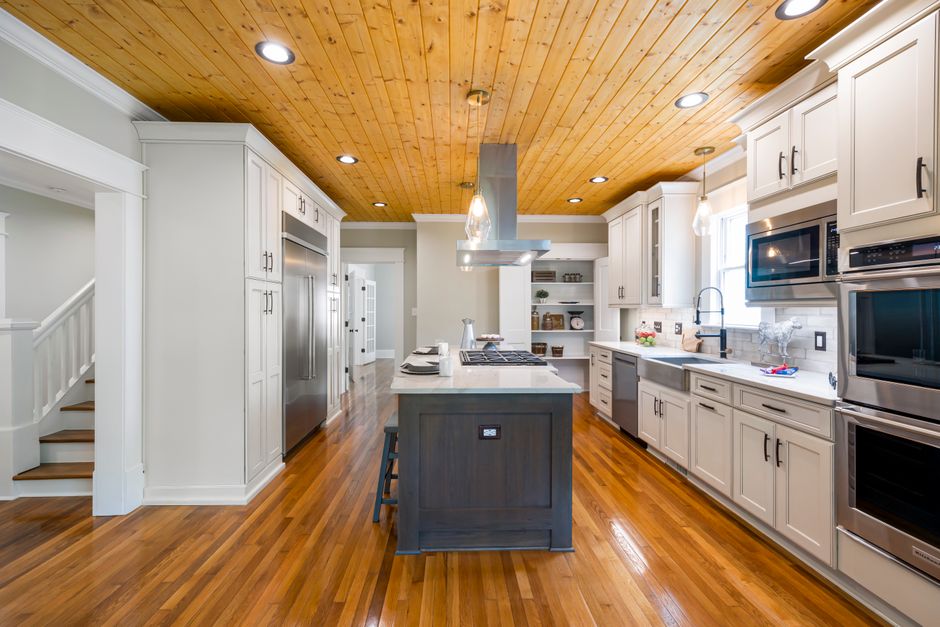 Spacious modern kitchen featuring a wooden ceiling, island countertop, and stainless steel appliances.